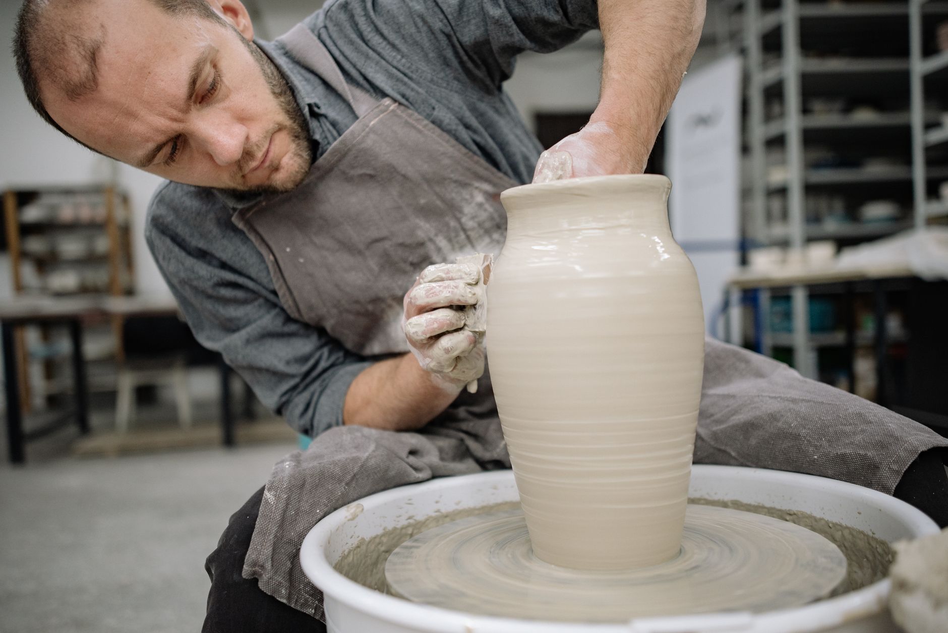 A ceramicist shaping a piece on the wheel in her studio