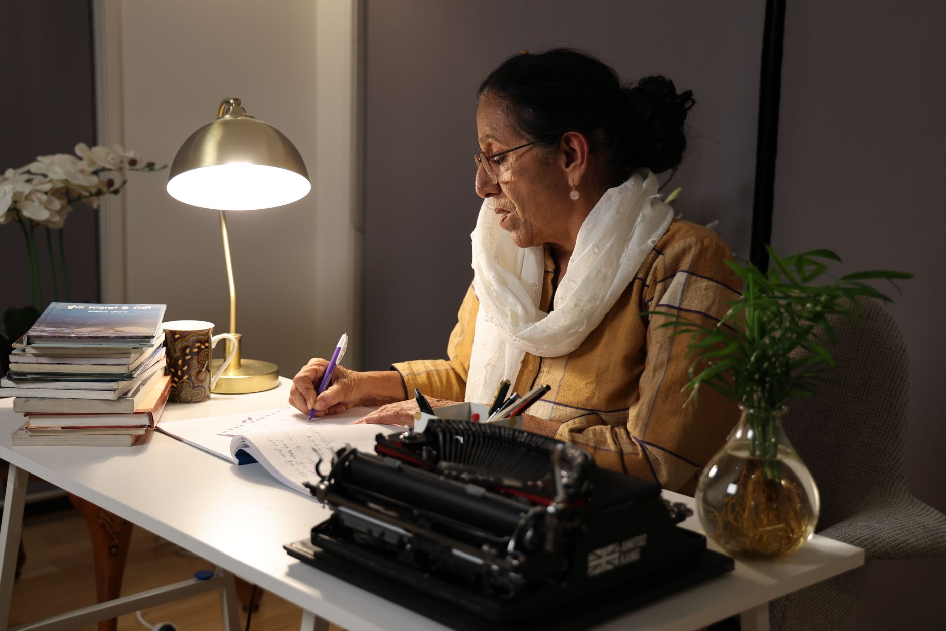 An author working at a desk surrounded by drafts and finished books