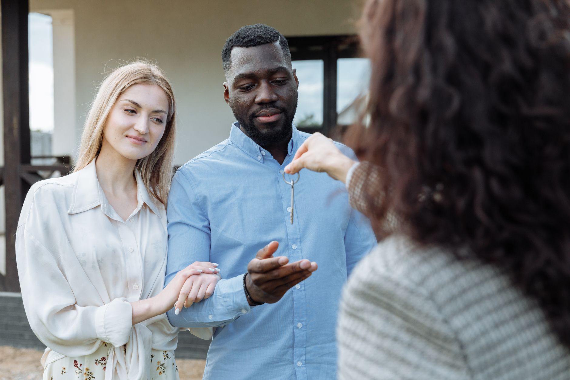 An estate agent handing over keys to new homeowners outside a house