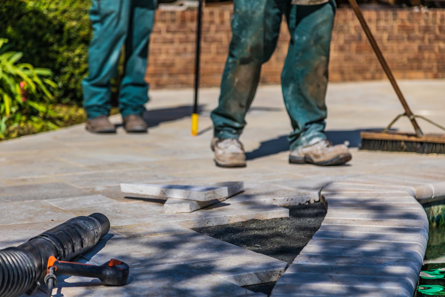 A landscaper carefully laying a stone patio in a customer's garden