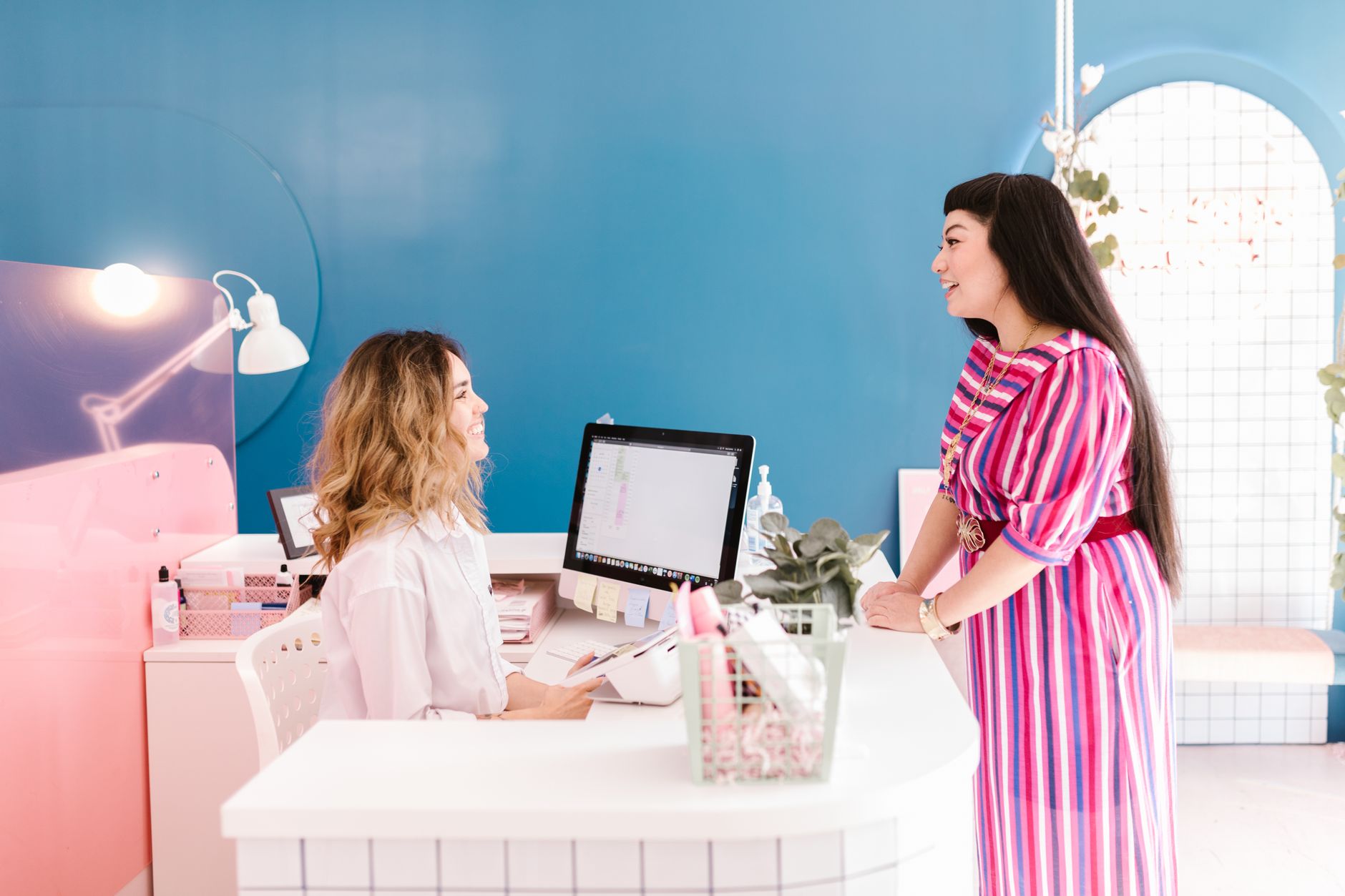 A salon owner welcoming a client at the reception desk