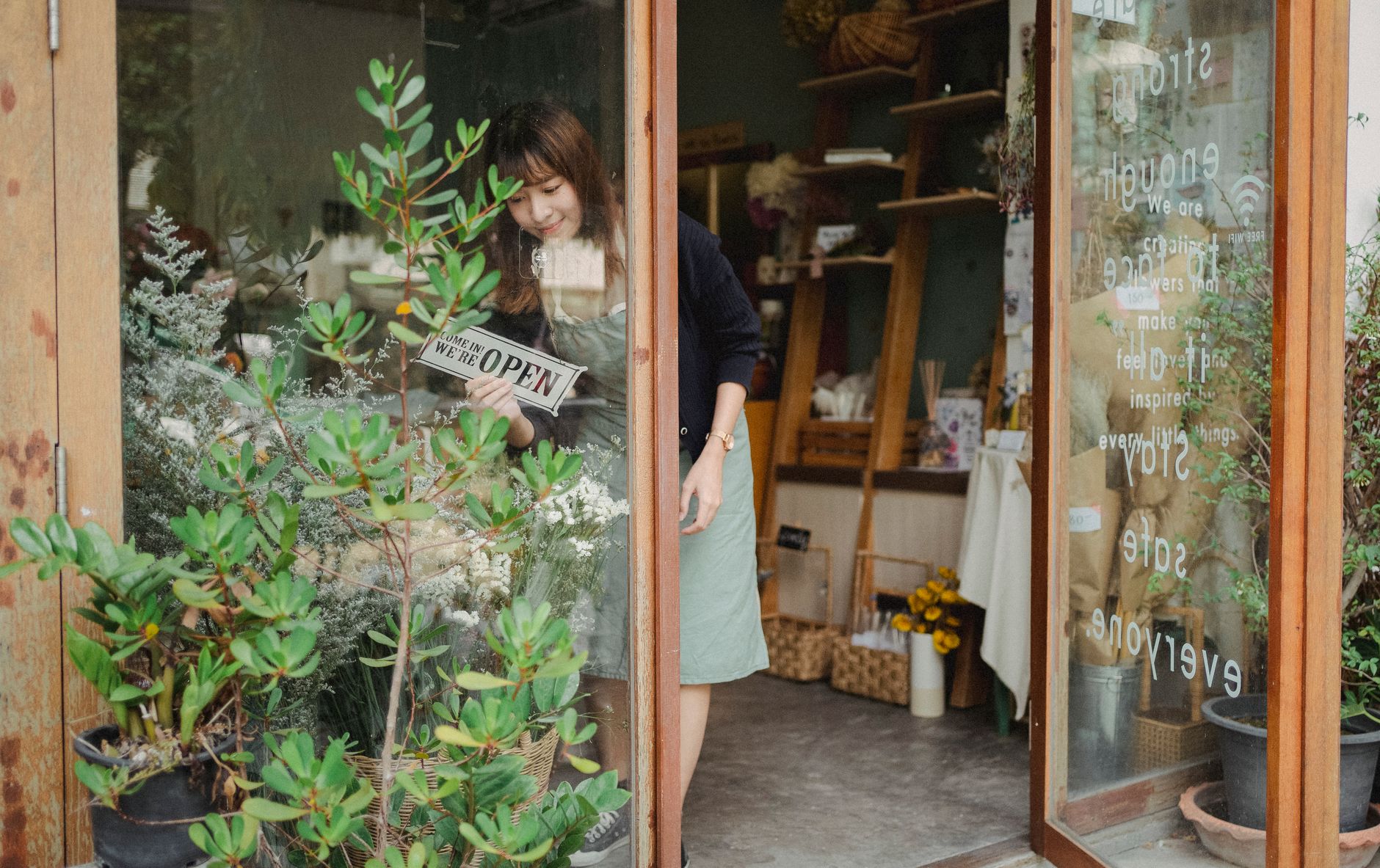 A shop owner setting up a fresh window display with a handwritten offer