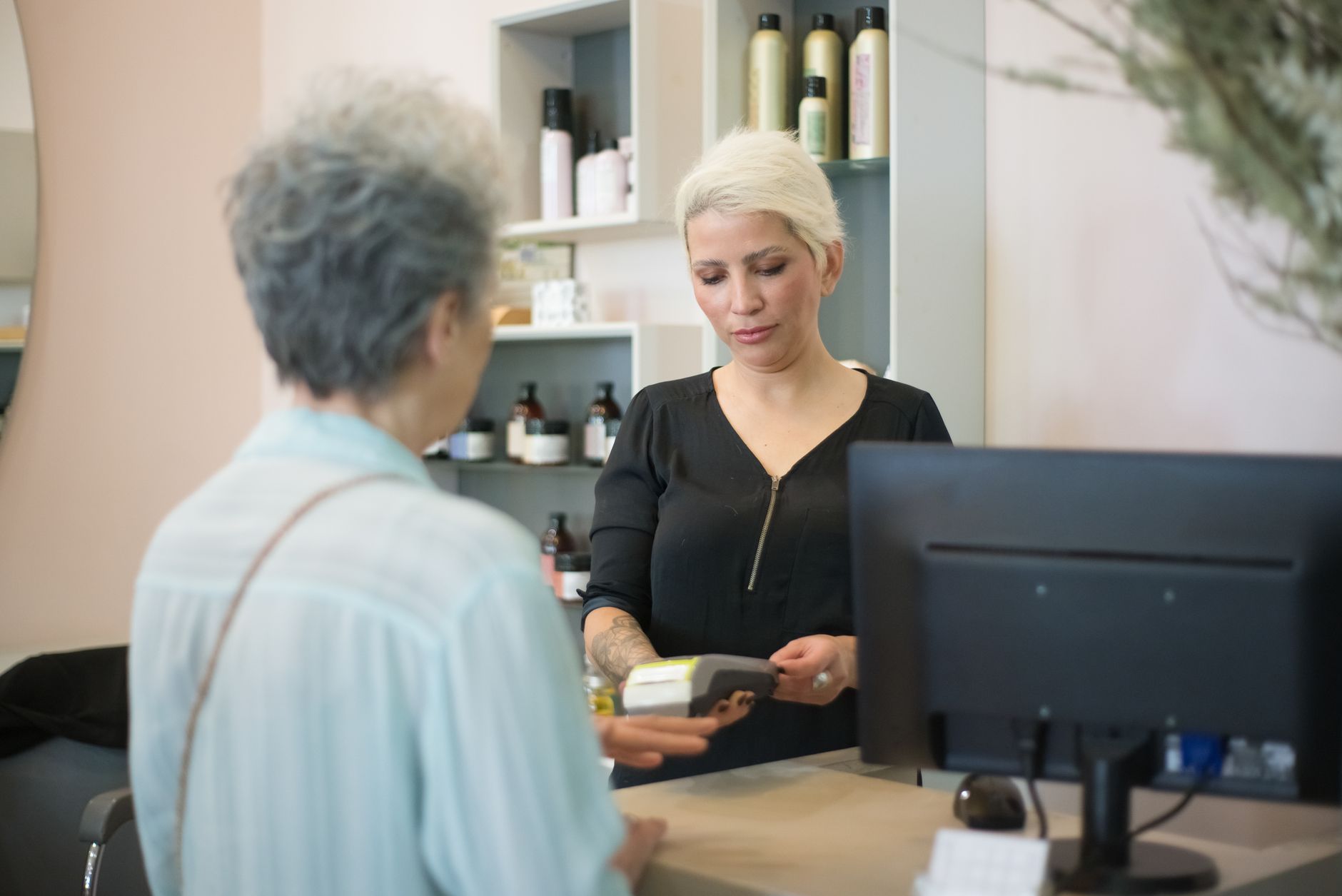 A shop assistant scanning a customer's loyalty card at checkout