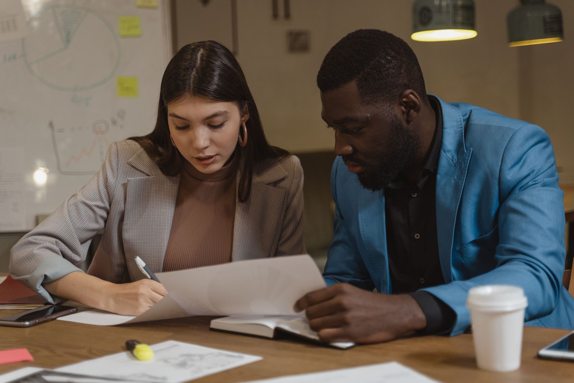 Two colleagues reviewing sales notes together at a desk