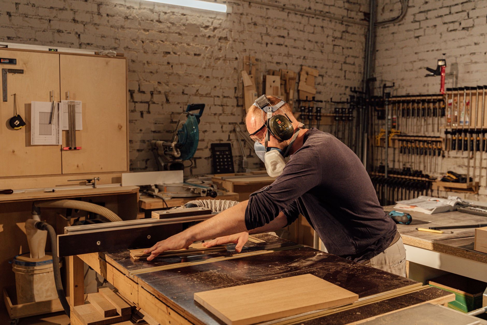 A furniture maker clearing sawdust in a small workshop