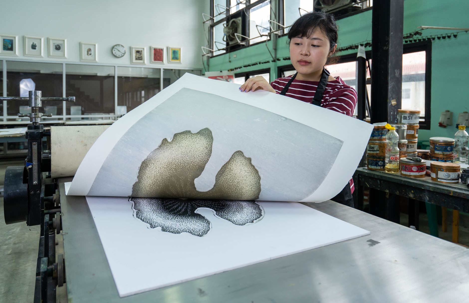 A printmaker checking a print carefully for imperfections