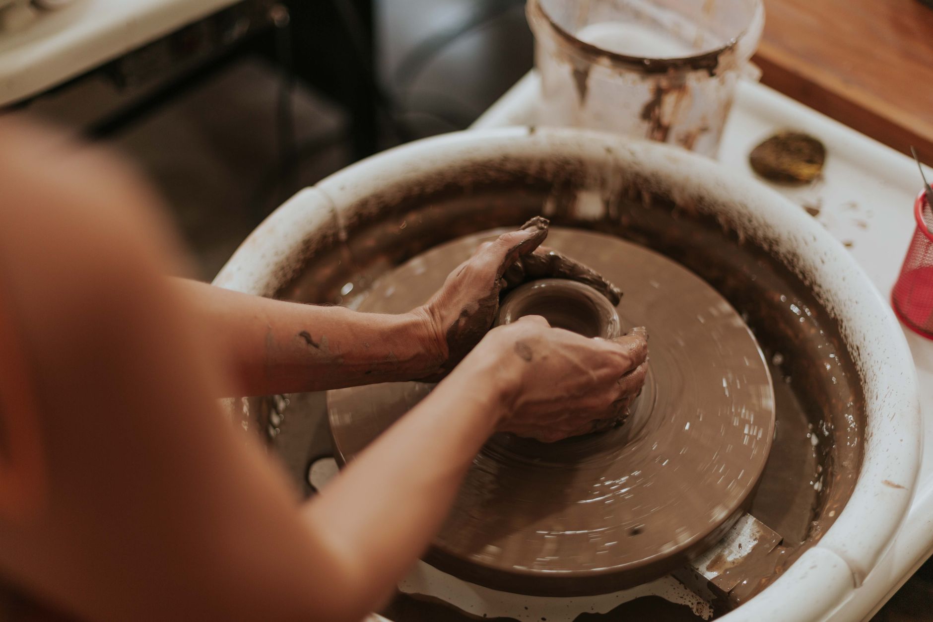 A ceramicist filming their own hands shaping clay on the wheel