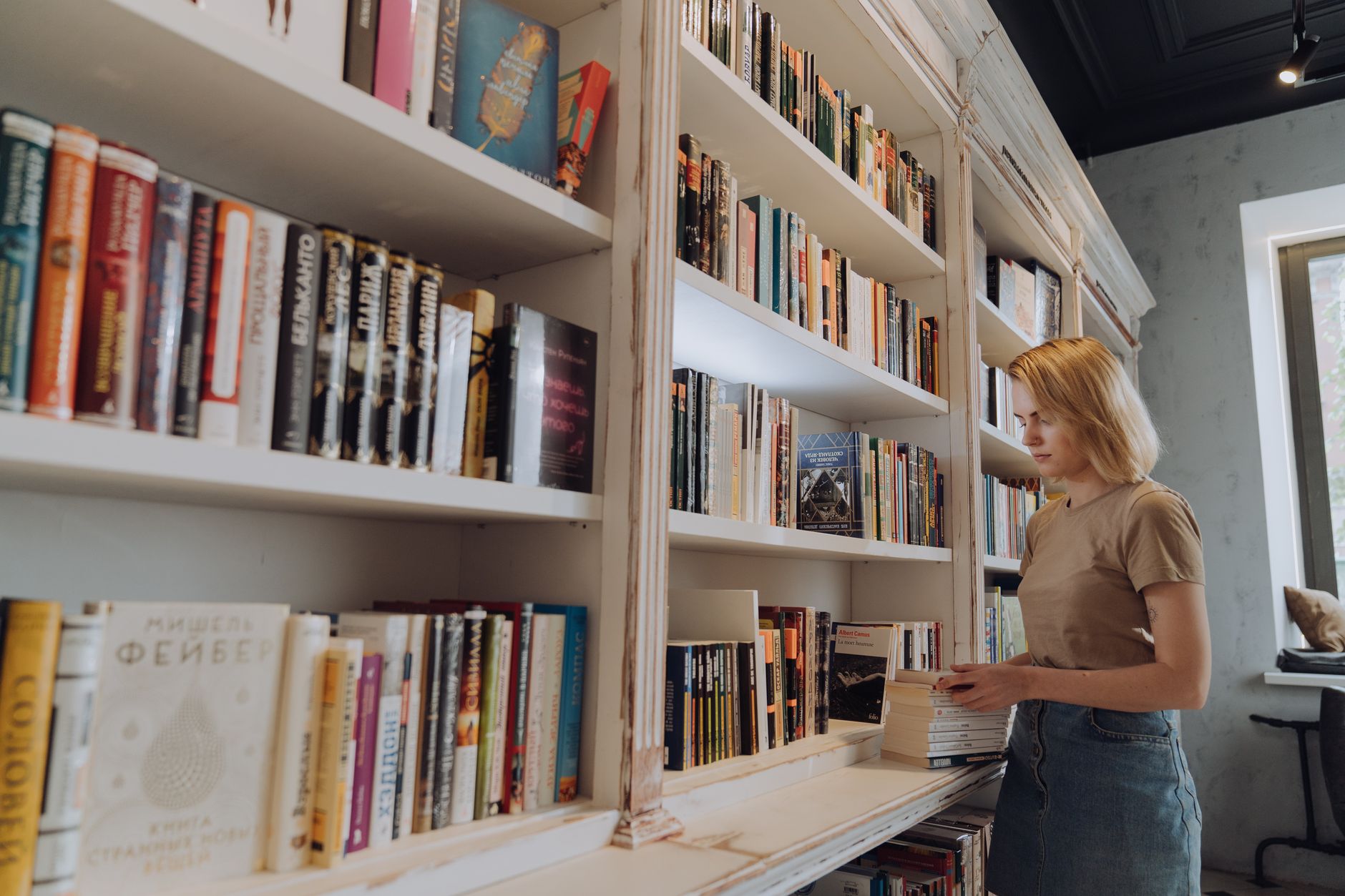 A bookshop owner arranging a shelf of staff recommended books