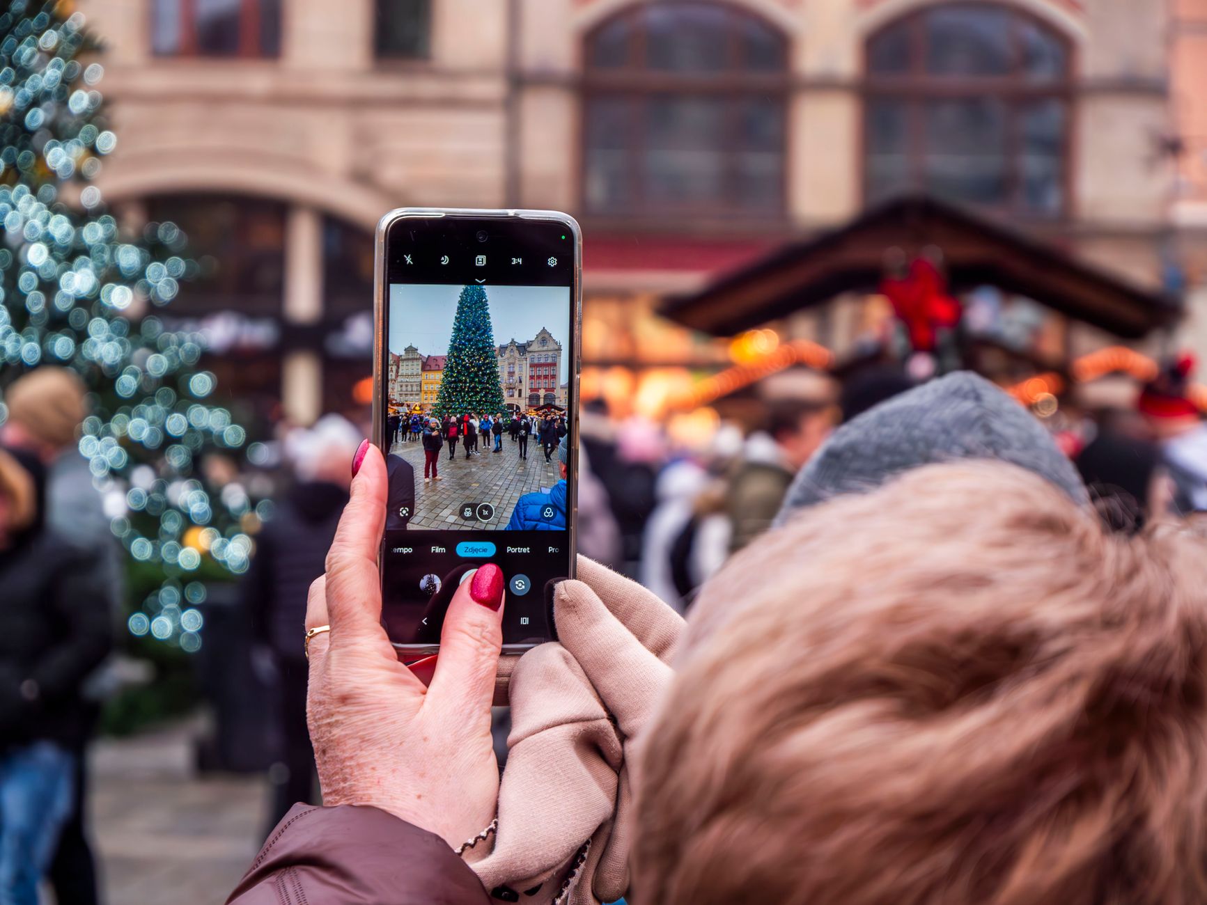 A shopper checking their phone for gift ideas at a Christmas market