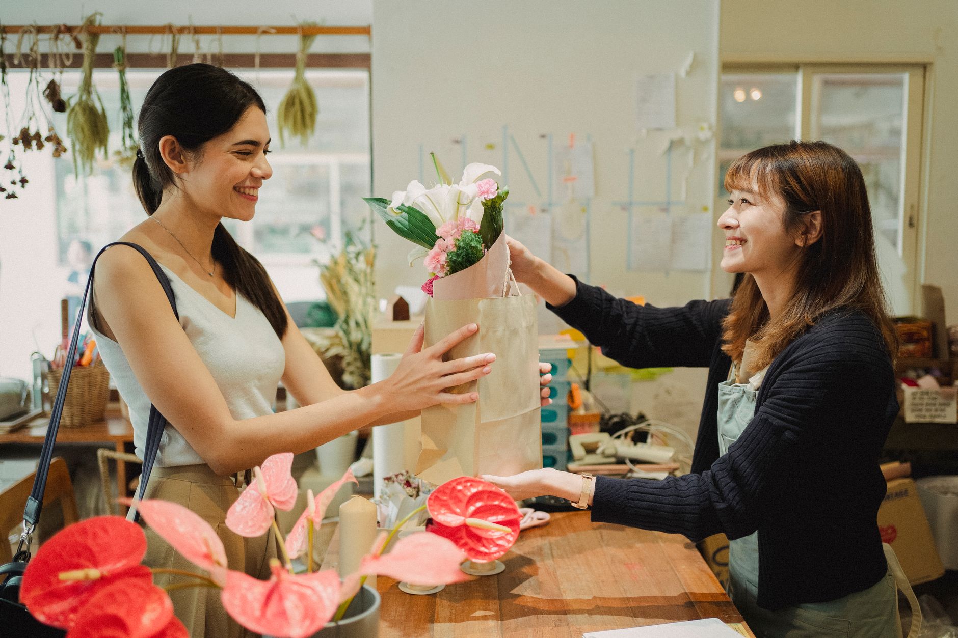 A florist handing over a bouquet to a customer in her shop