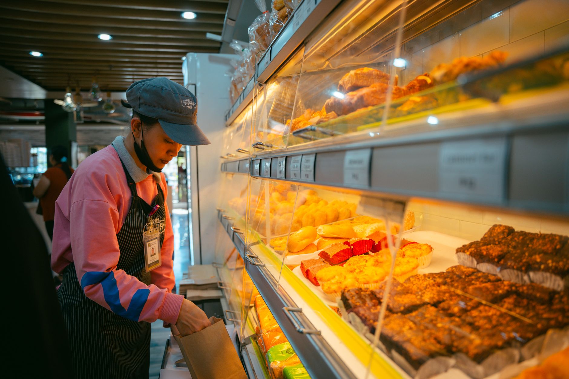 A baker adding a free extra item into a loyal customer's order