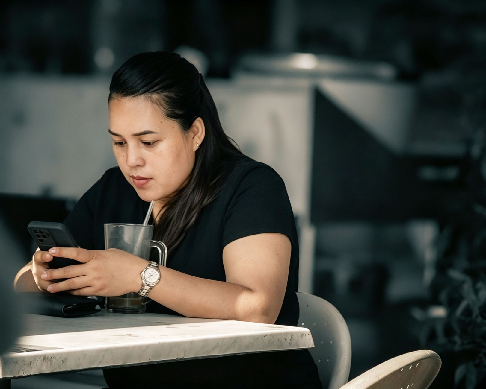 A woman sitting in a cafe browsing on her phone
