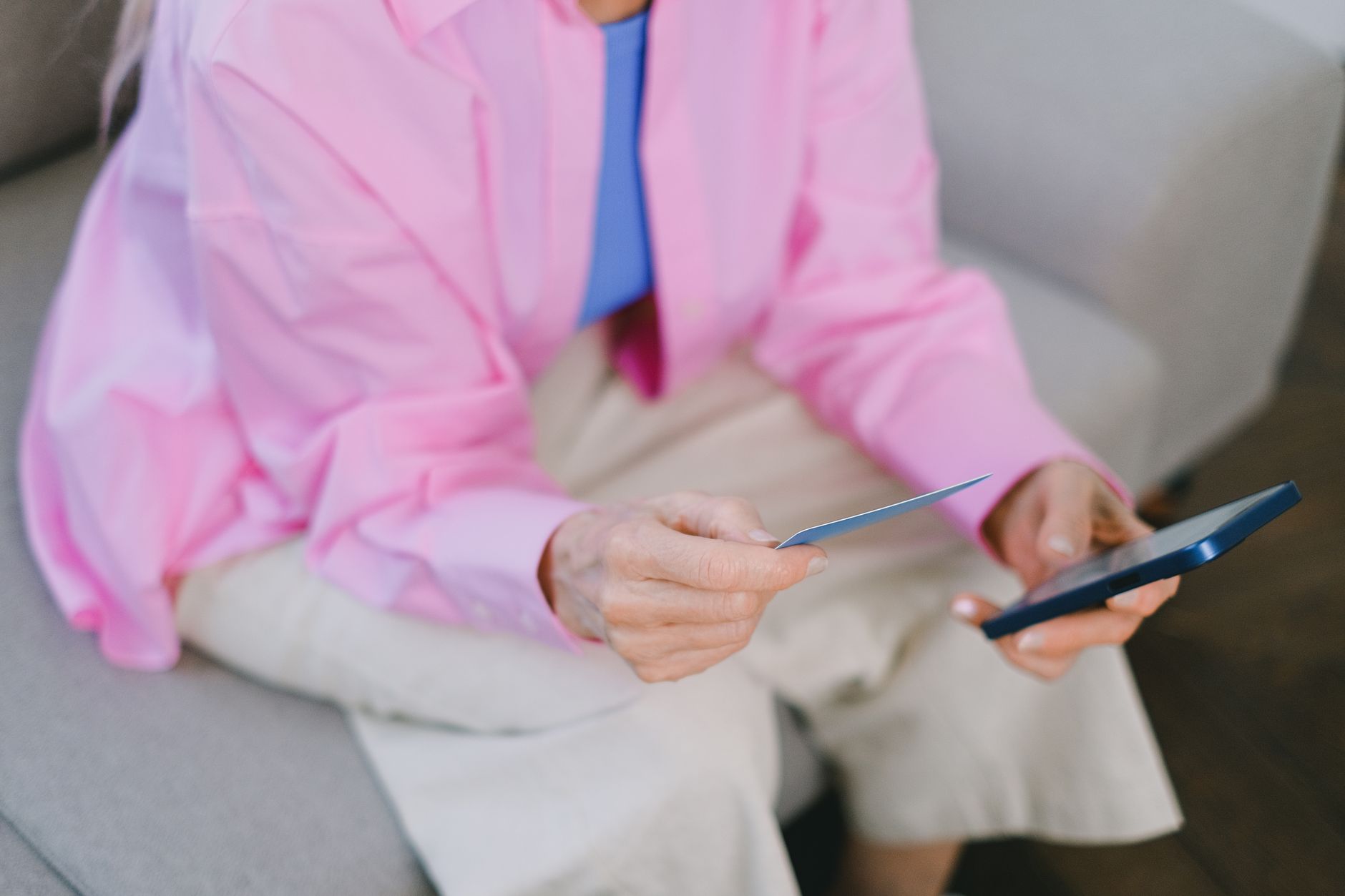 A woman on a sofa shopping online with a payment card in her hand