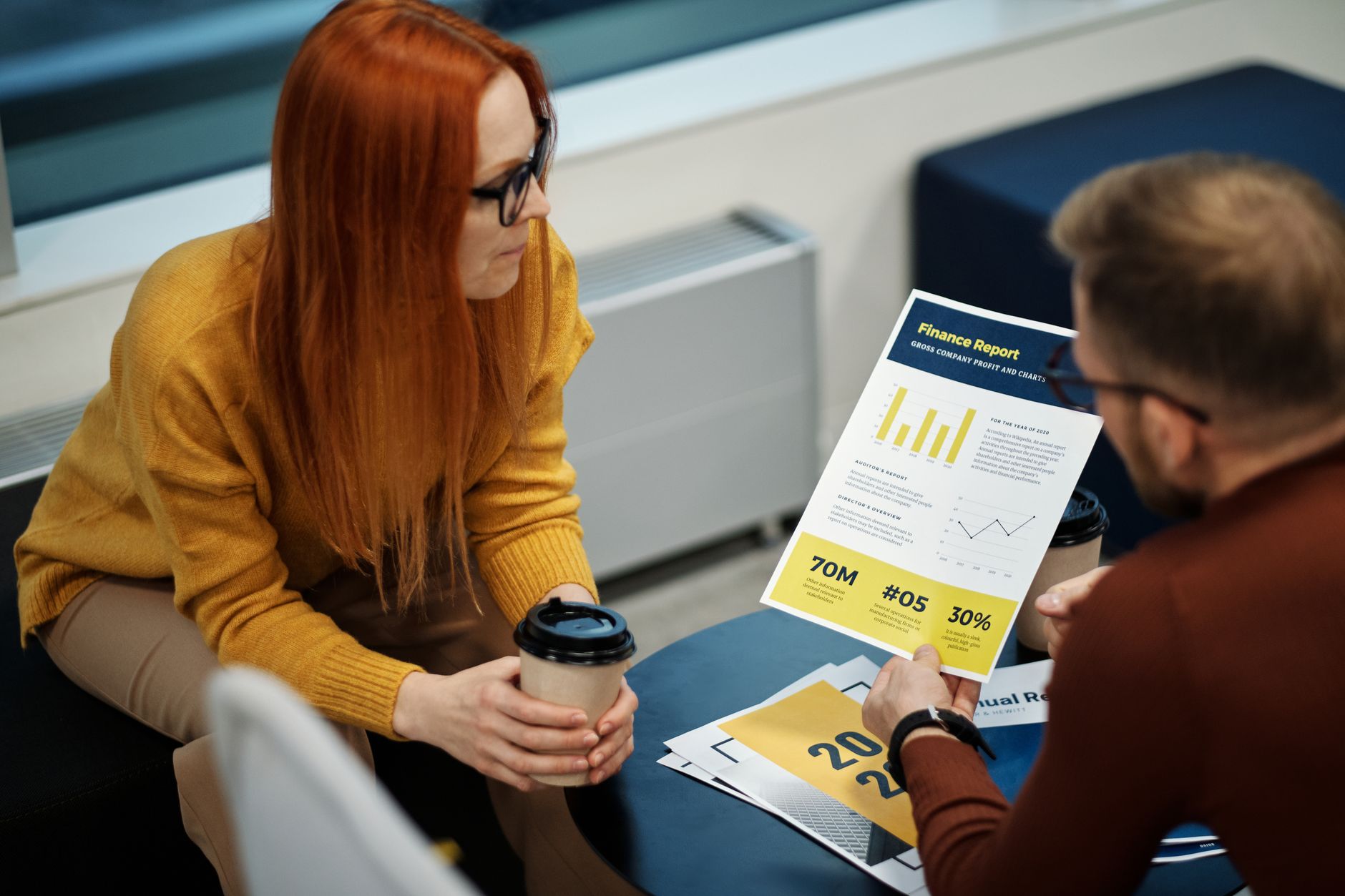 Two people sitting at a desk reviewing printed sales charts together