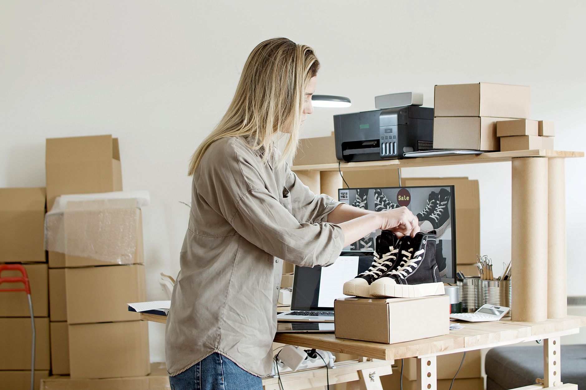A small online store owner packing customer orders at a workbench in a home studio
