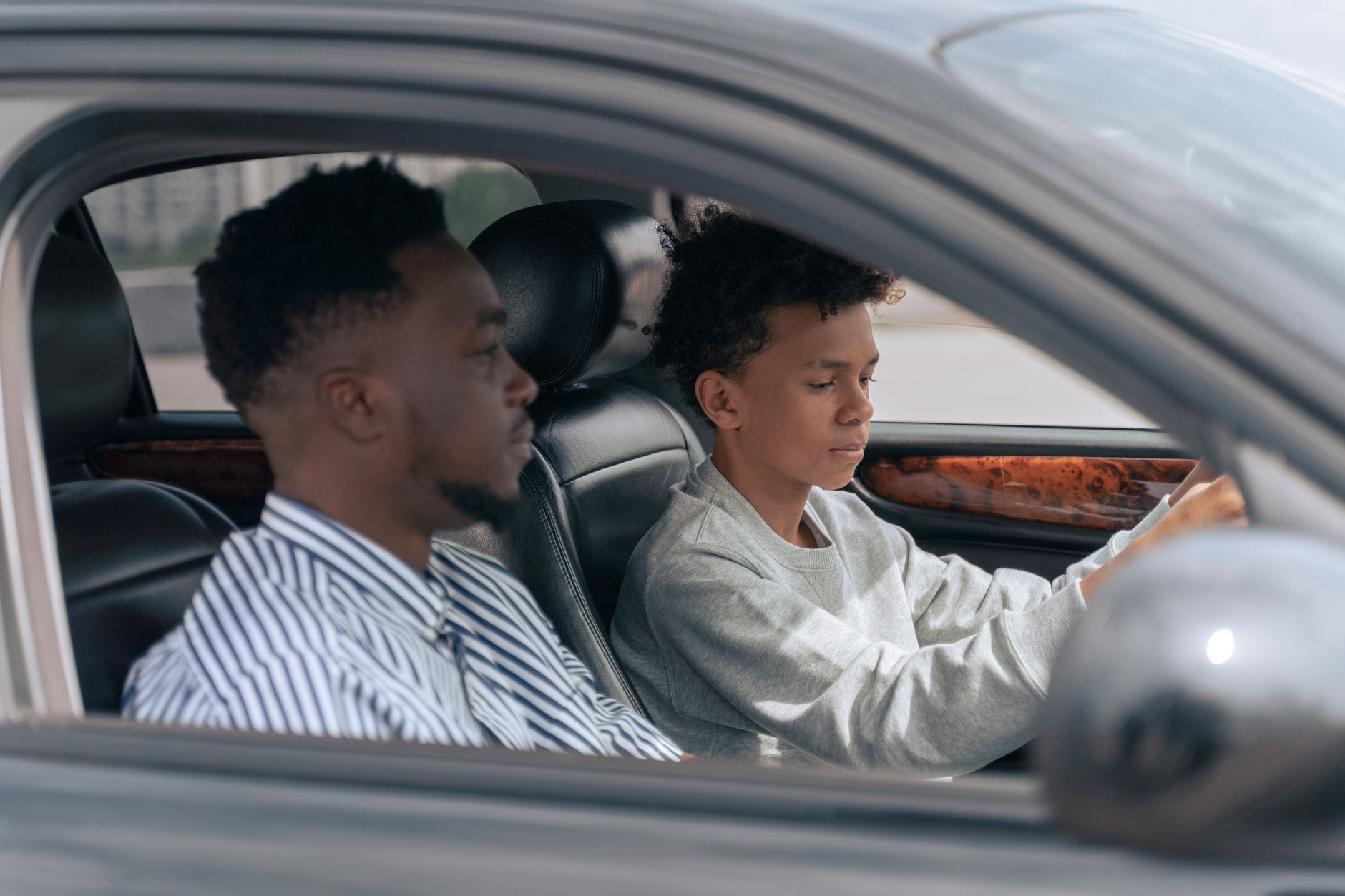 A driving instructor discussing lessons with a parent and their teenager