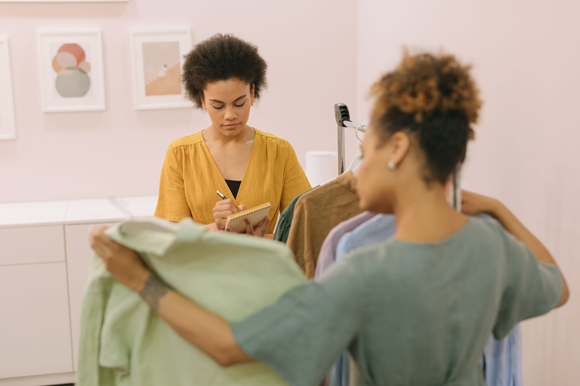 A boutique owner taking a phone enquiry while a colleague records it