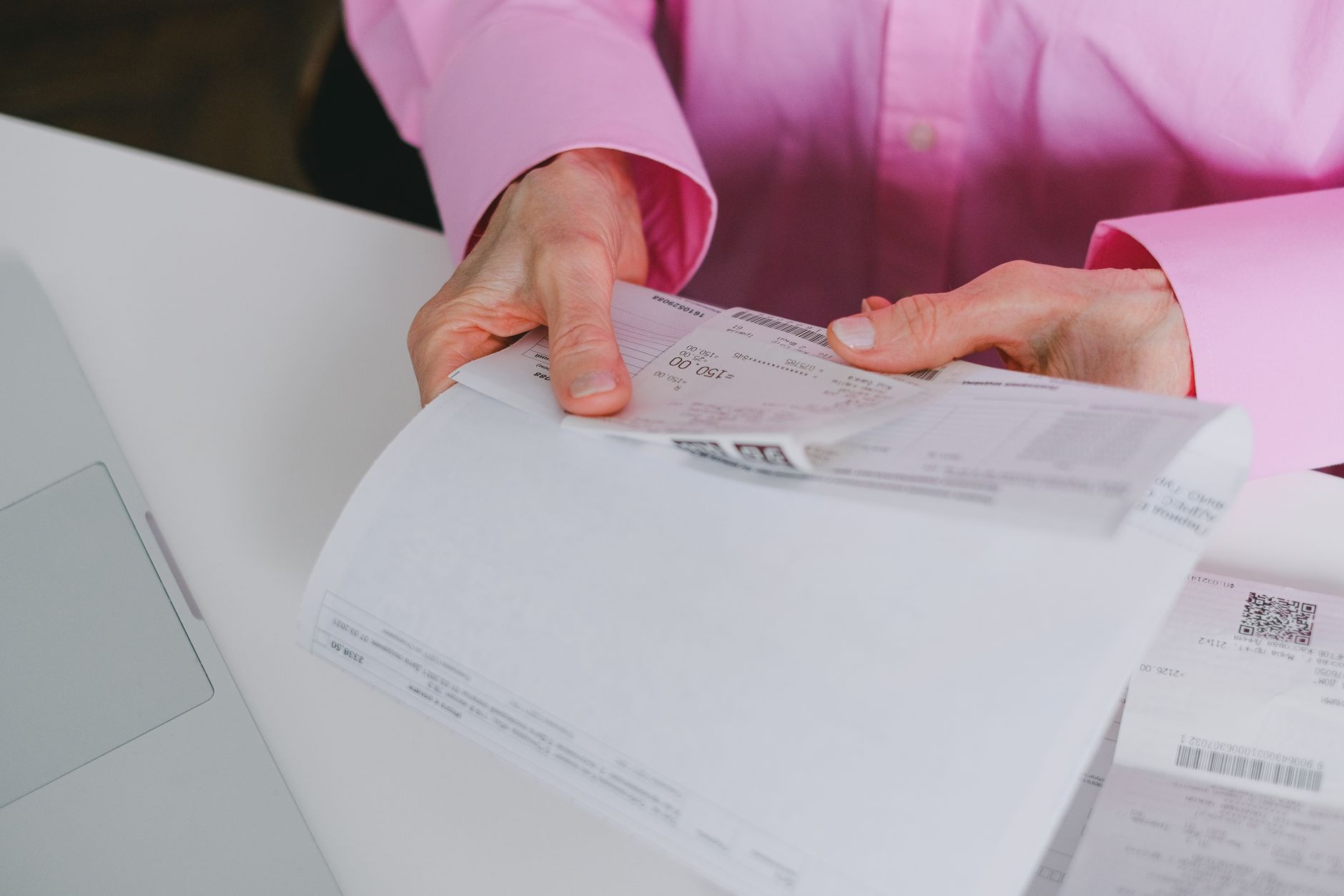 A person looking over paper invoices and receipts at a table, the costs new owners often forget