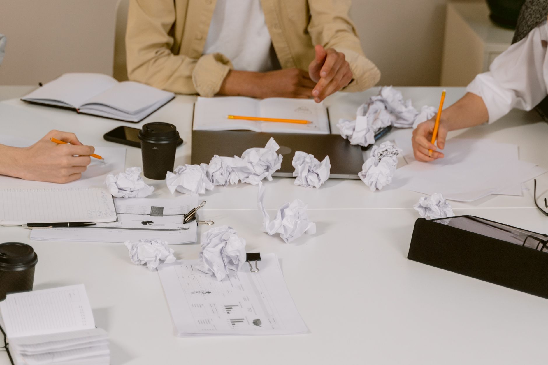 Crumpled paper notes beside a coffee and a notebook, deciding where not to spend early
