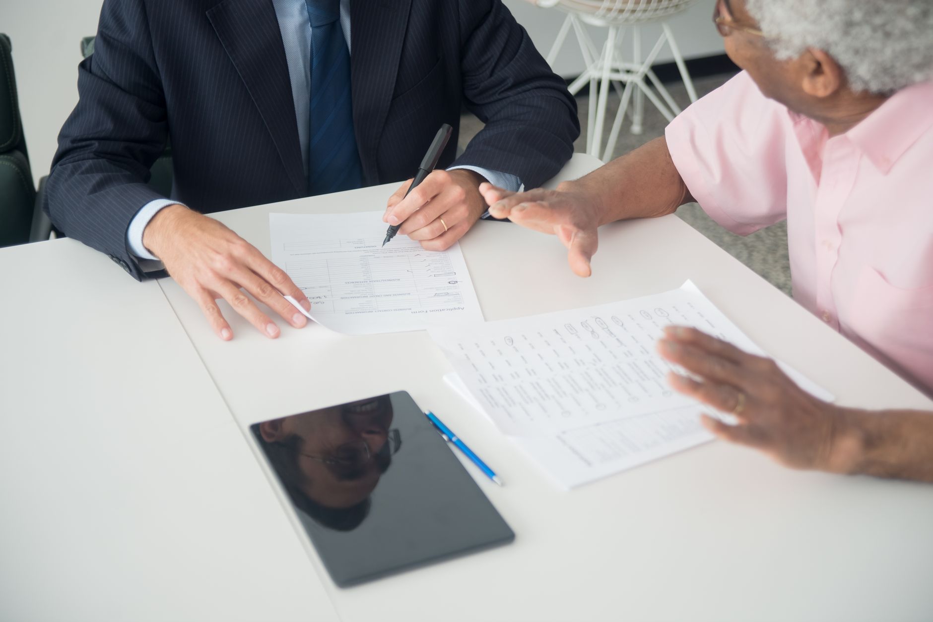 Two people talking over paperwork at a table, weighing up ways to fund a new business
