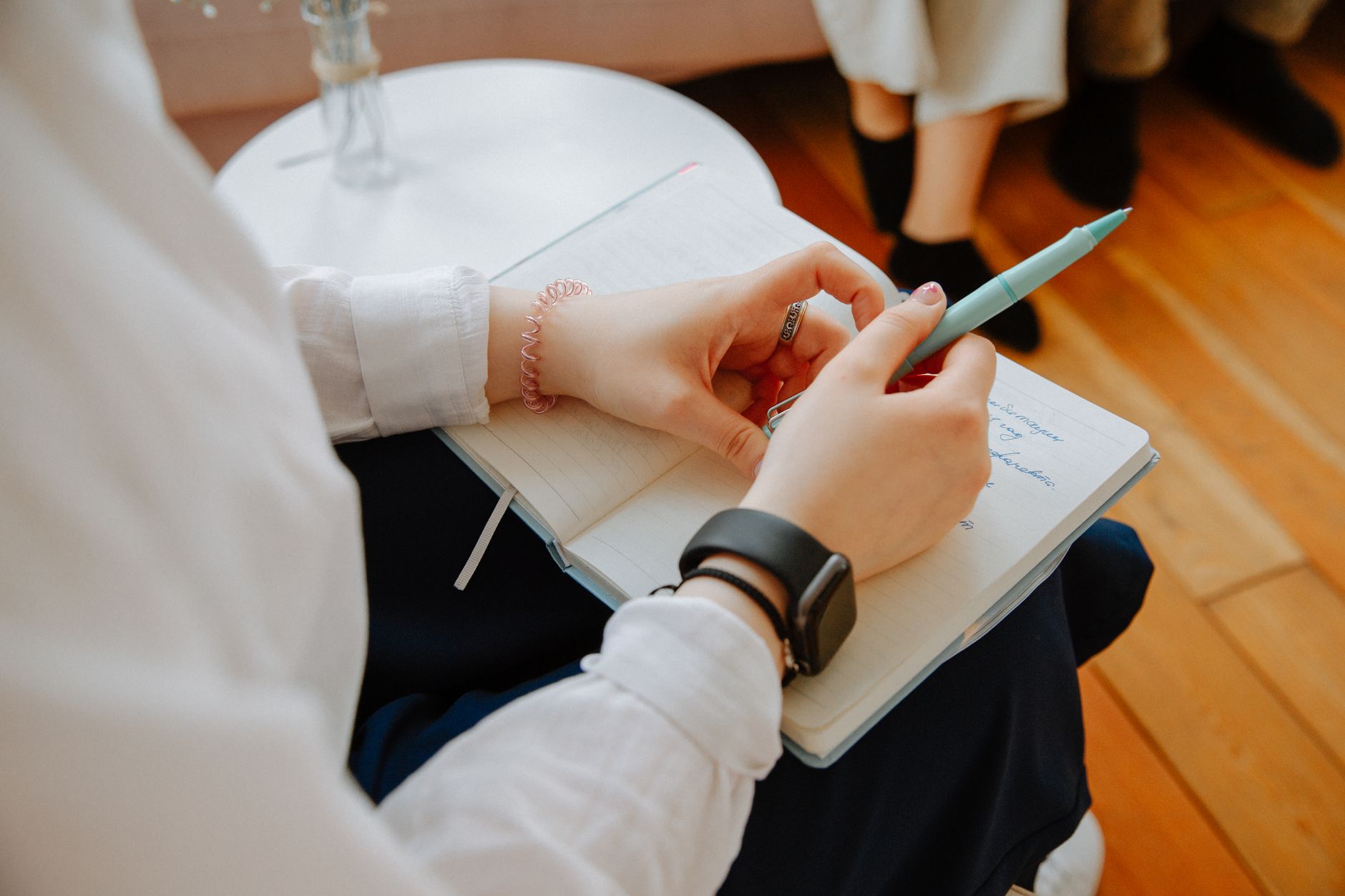 A therapist sitting at a tidy desk writing in a notebook, planning the focus and specialism of a private practice