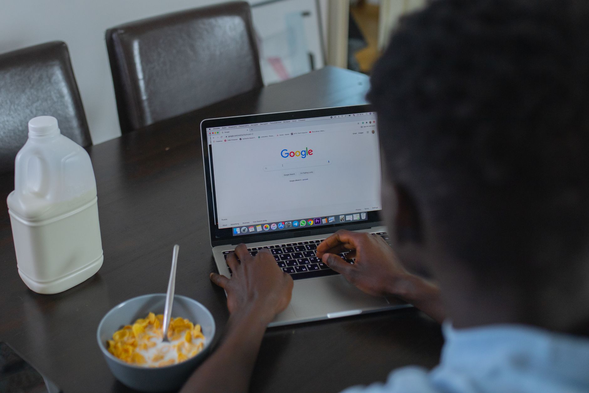 A person at a kitchen table searching on a laptop, browsing listings to find a local professional service