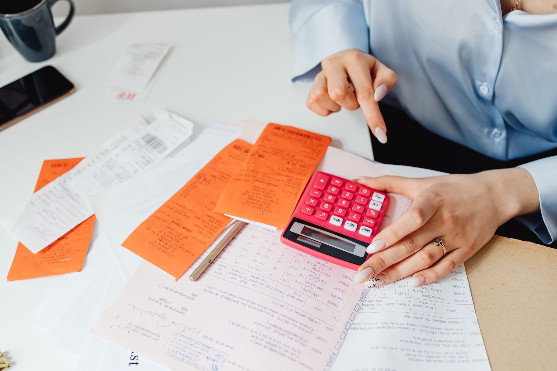 A bookkeeper works at a tidy desk with sorted receipts and a laptop open to an accounts spreadsheet, calm and in control of the paperwork.