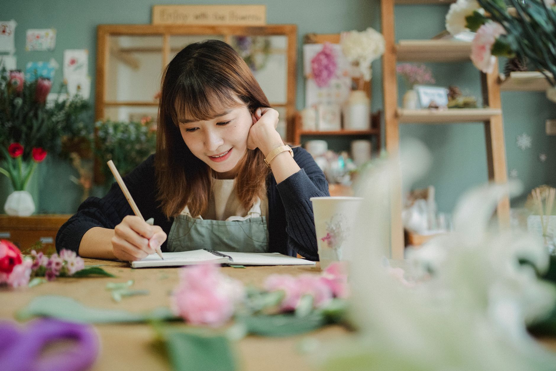 A new service business owner reviews a steadily rising client count in a notebook at her desk, planning her next outreach step.