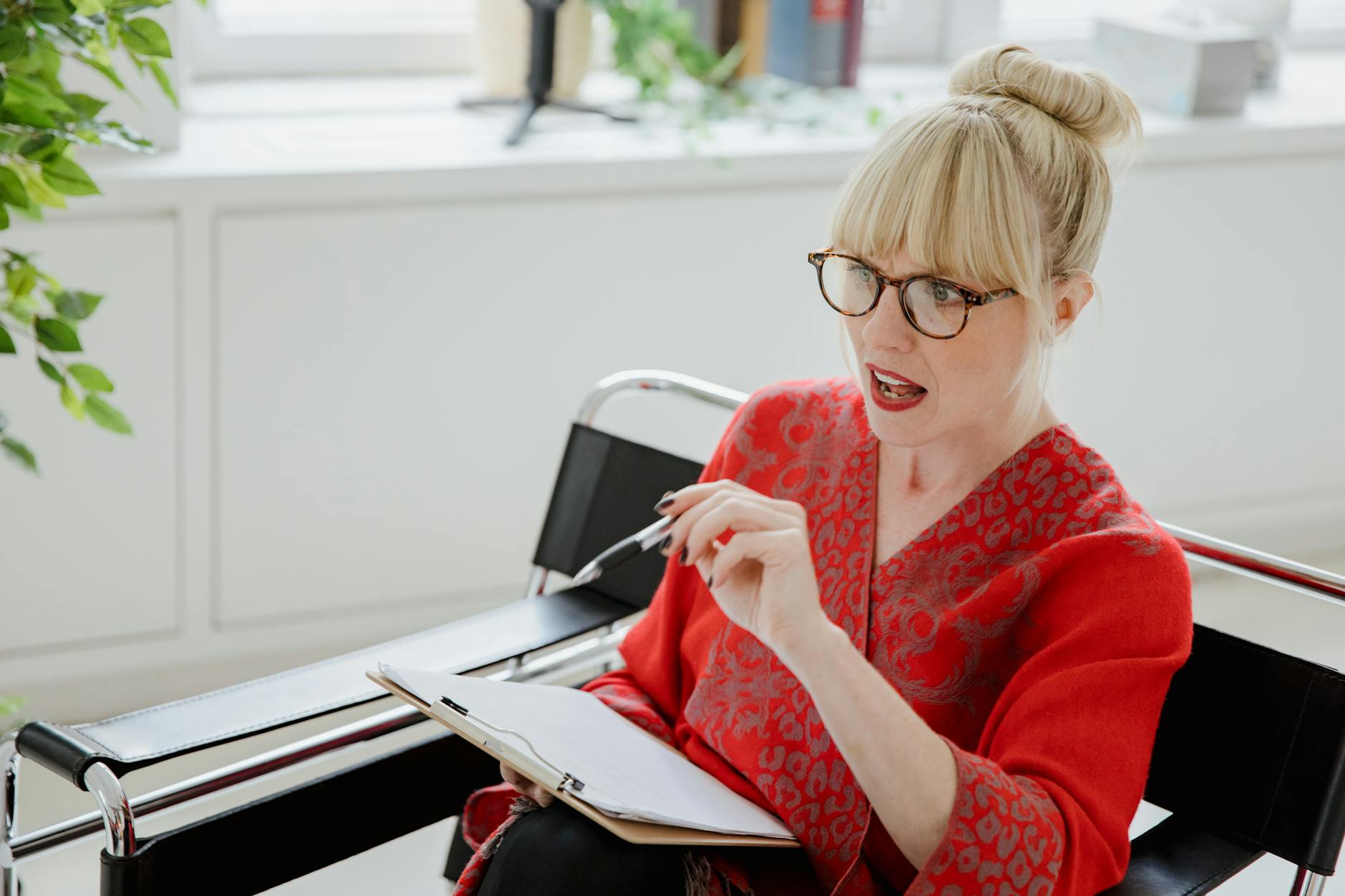 Woman in red outfit discussing documents in a modern office setting. Professional and engaging.