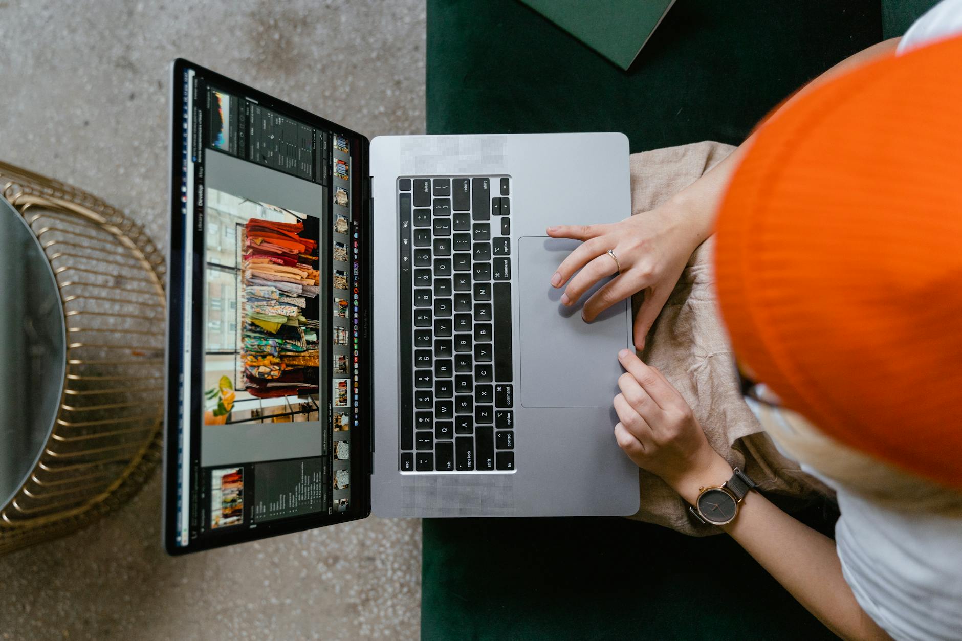 Person wearing orange beanie editing photos on laptop using professional software.
