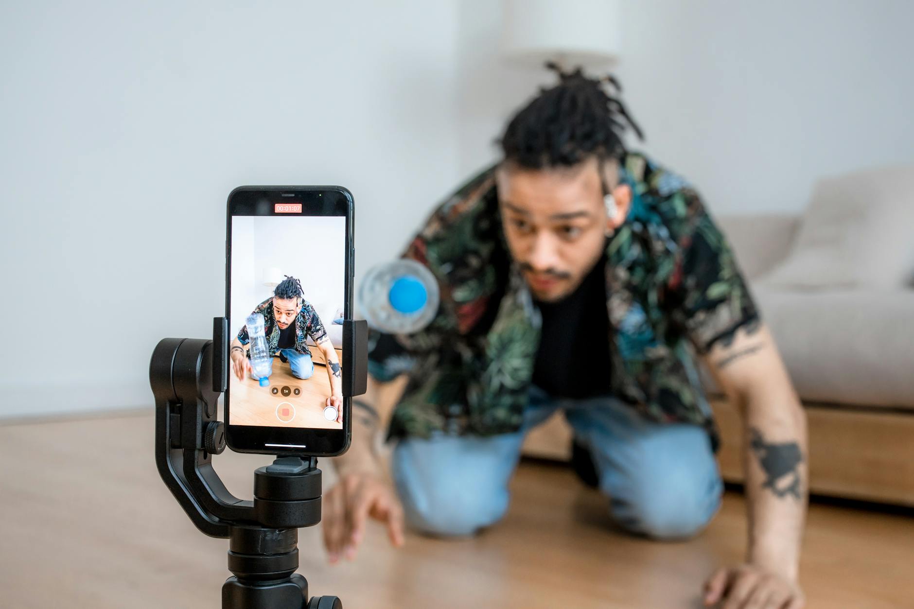 Man filming creative content with smartphone on gimbal indoors.