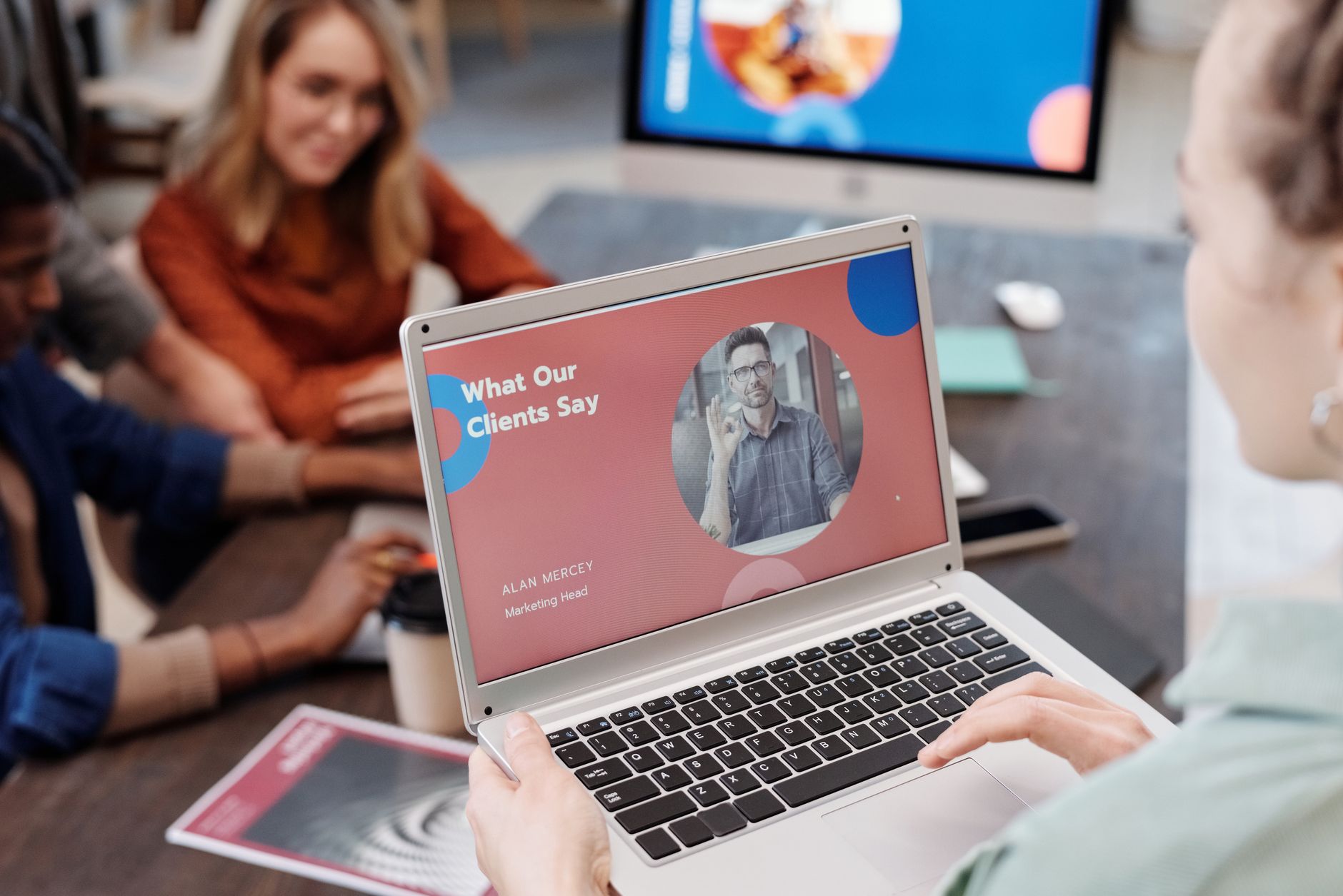 A freelancer presents the next stage of work to a returning client on a tablet across a small meeting table.