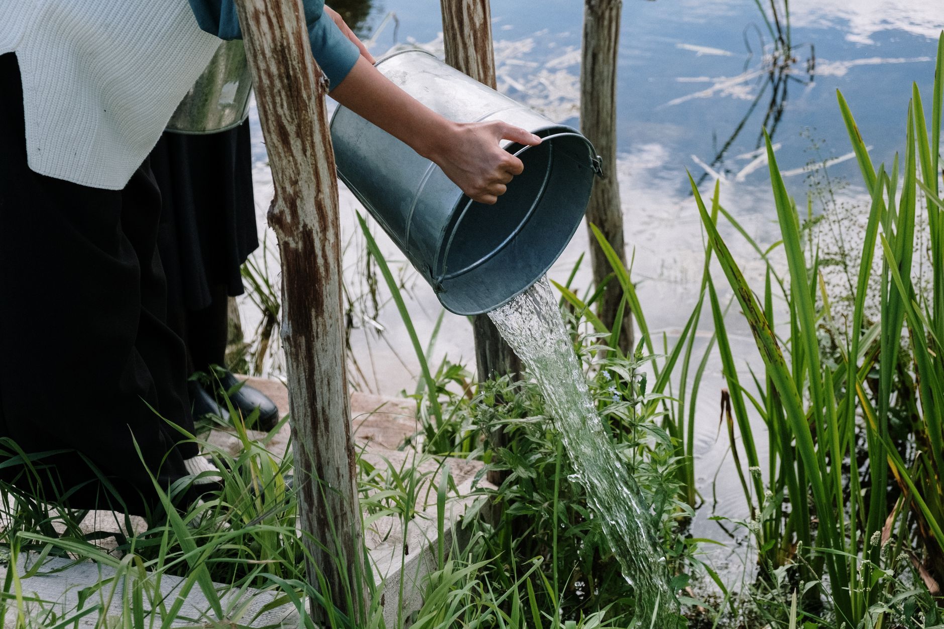 Water pours into a metal bucket while streams escape through holes in its side, illustrating effort lost through a leaky business.