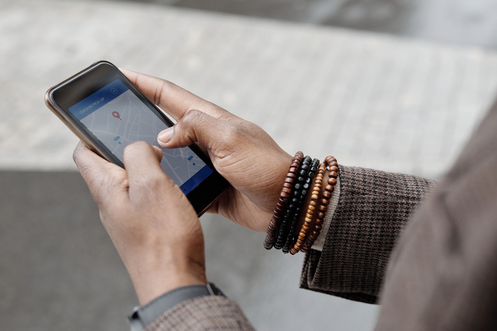 A customer holds a phone showing a local map search while standing on a high street, looking for a nearby business to visit.