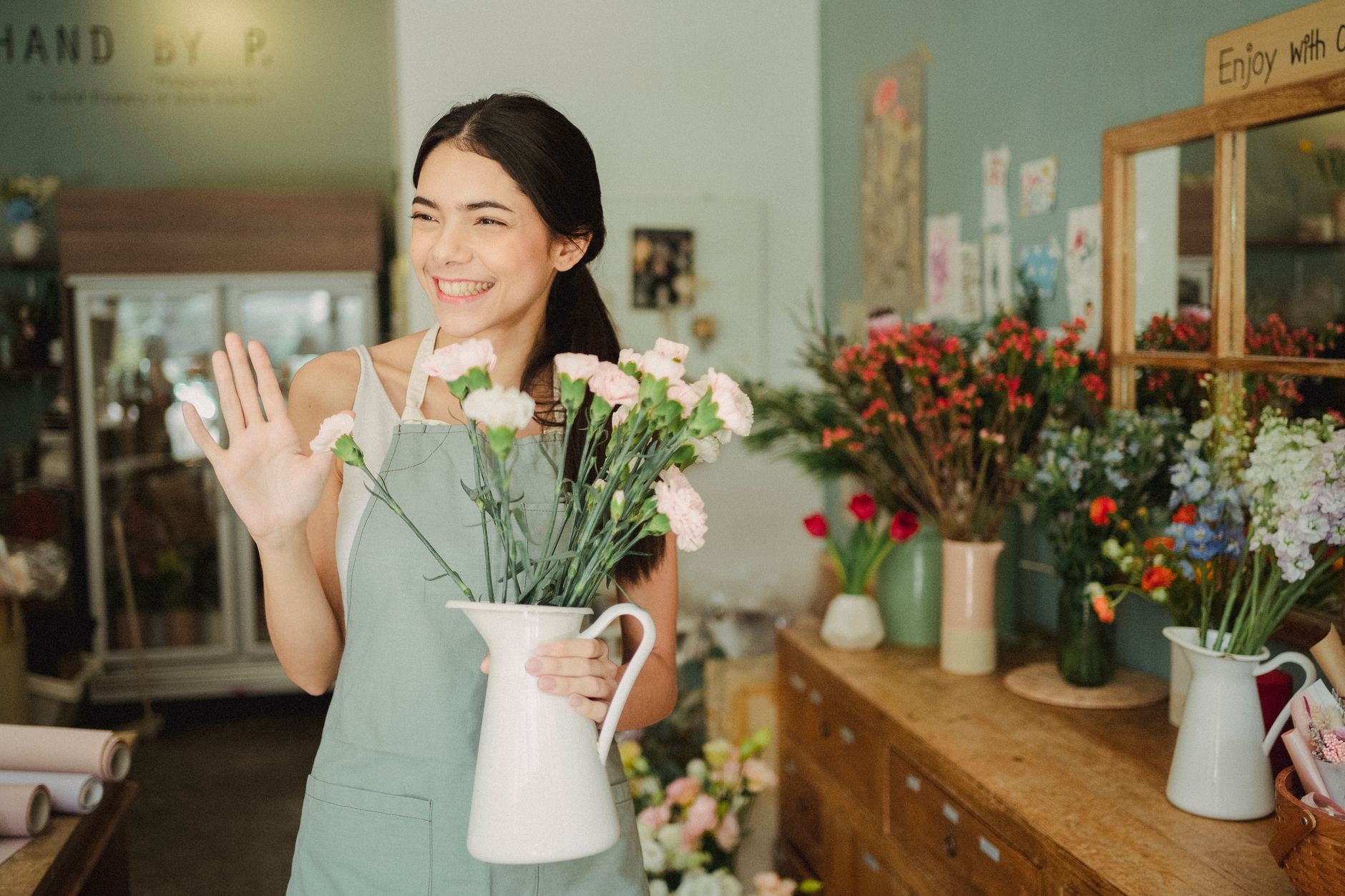 A shop owner warmly greets a returning regular customer by name across the counter of a small independent store.