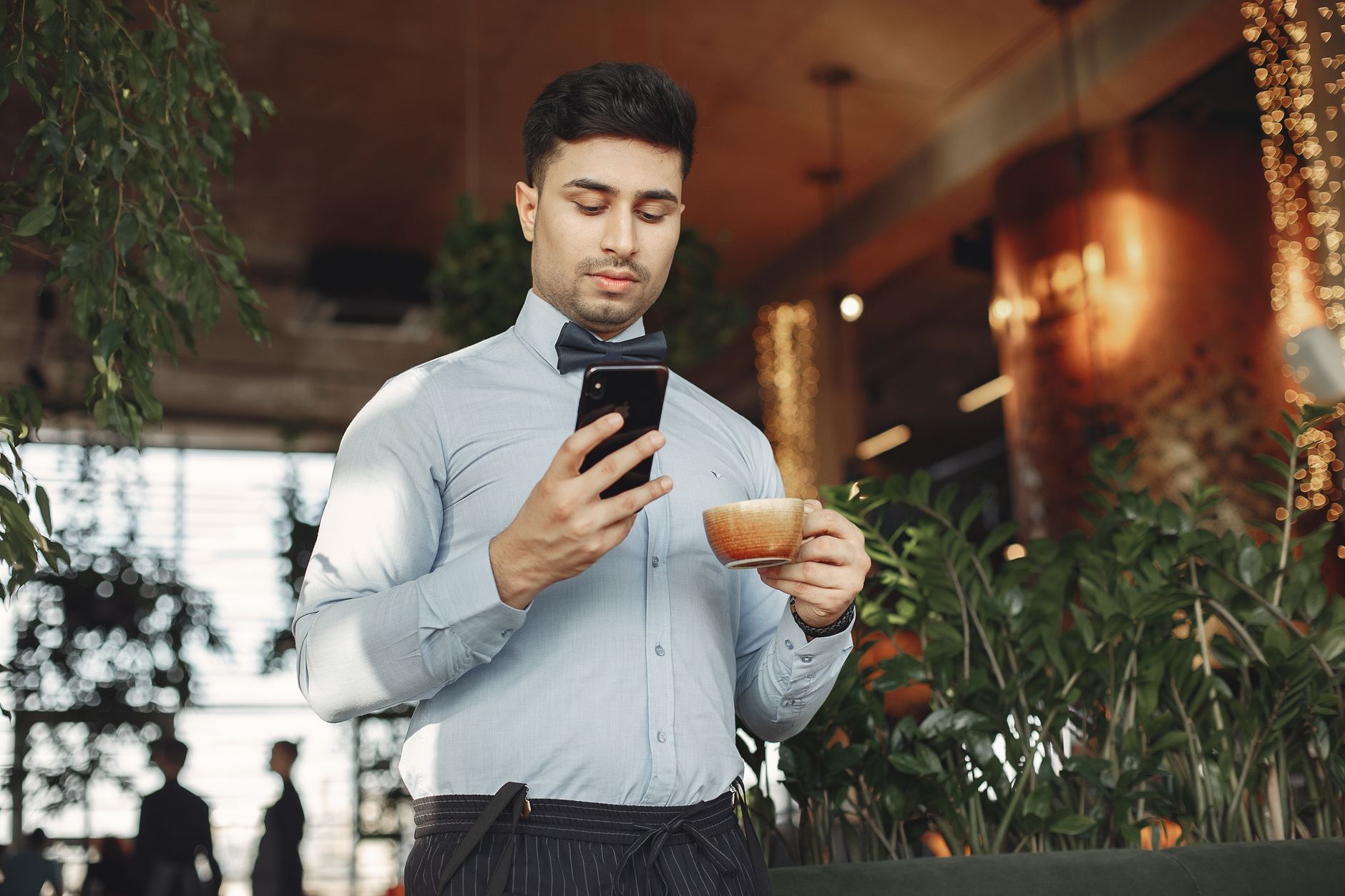 Customer sitting in a cafe reading business reviews and star ratings on a phone before choosing where to go