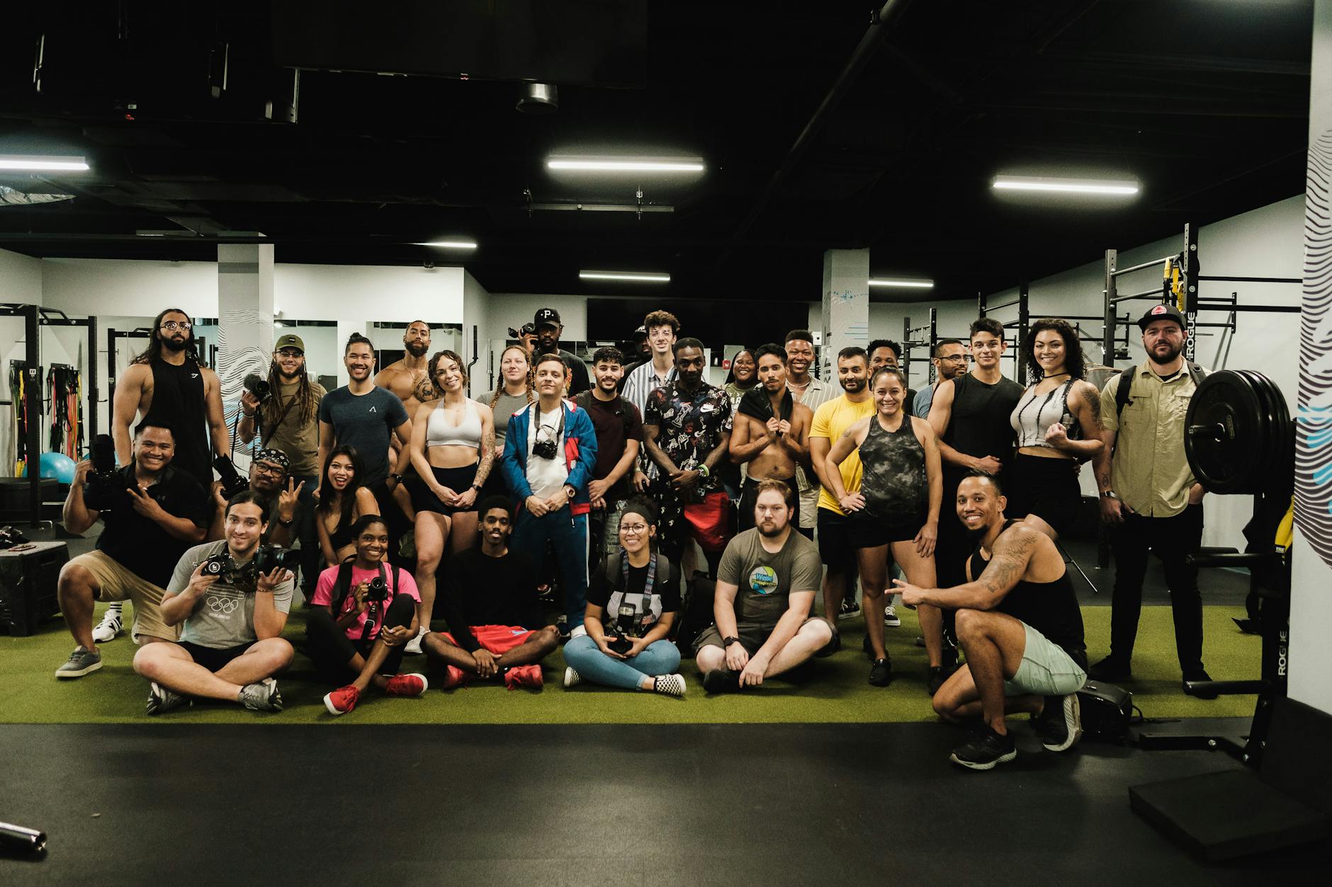 A large group of diverse adults smiling and posing together in a gym setting.