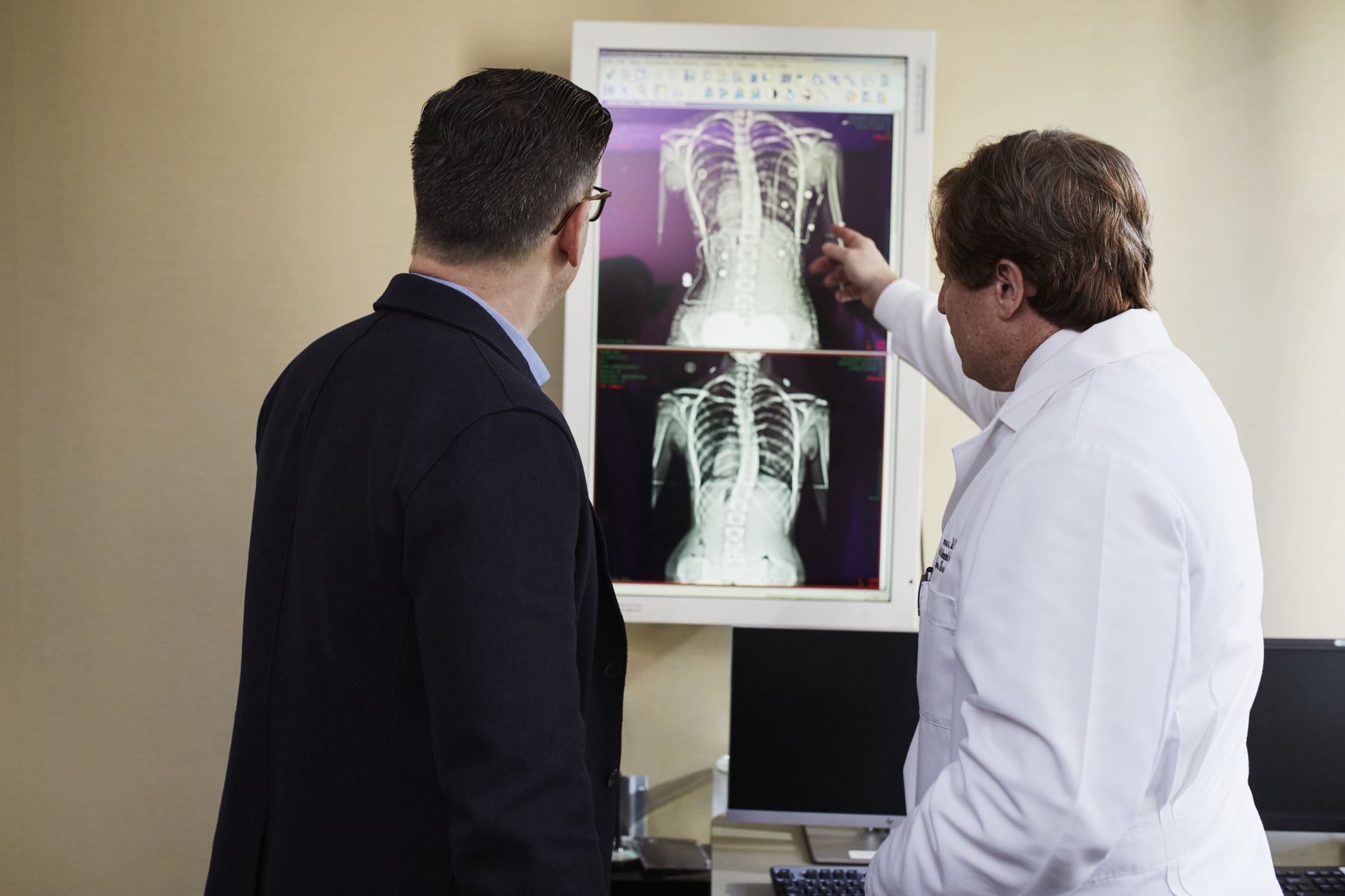 A doctor sits beside a patient in an unhurried consultation, explaining a treatment plan clearly and reassuringly.