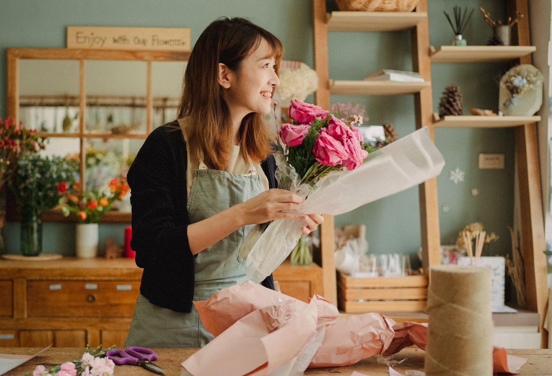 A florist arranges a bright bouquet on a workbench while filming the process on a phone, putting a personal spin on a trending format.