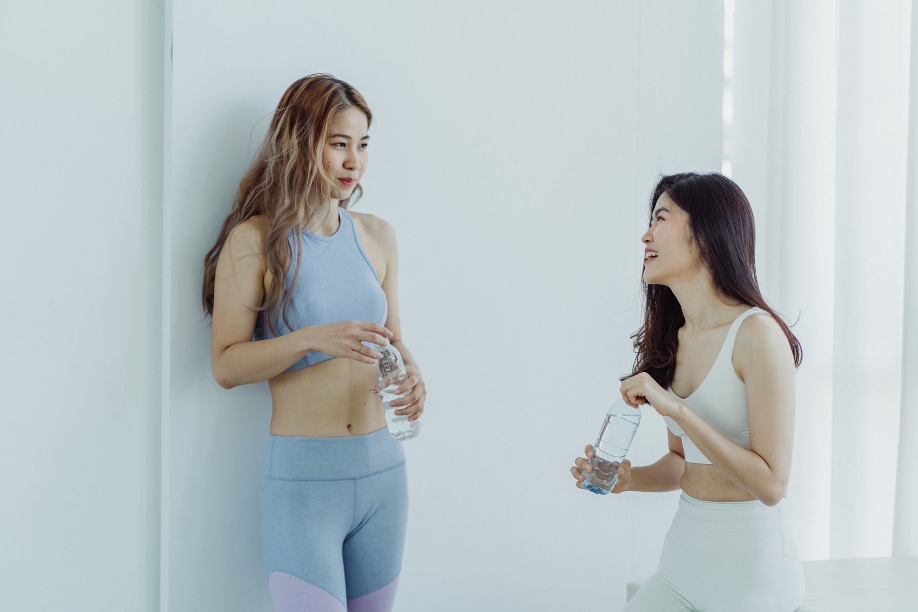 Two friends chat after a workout, one recommending their personal trainer to the other in a natural word-of-mouth moment.