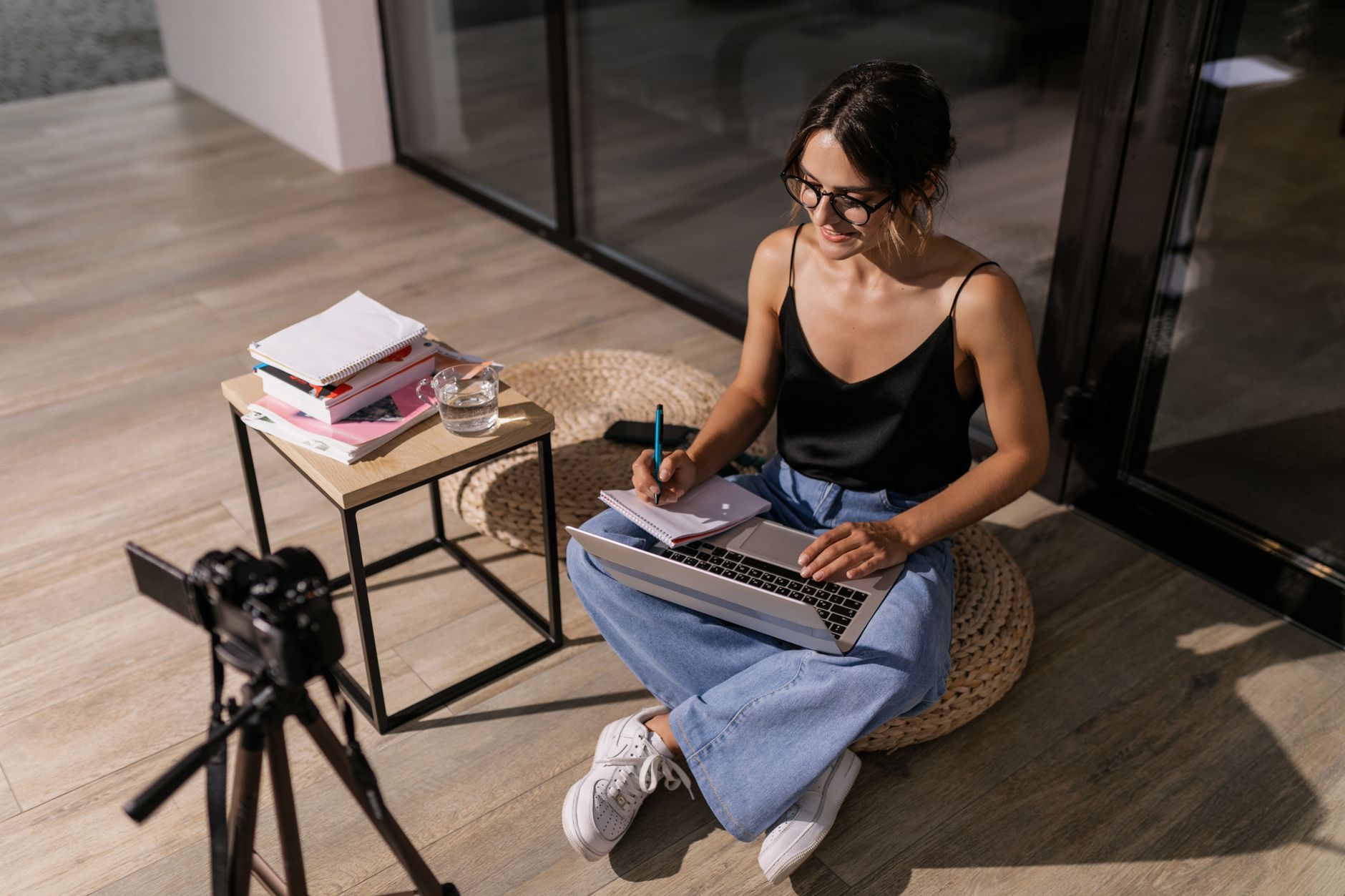 A coach records a piece of online content at a desk with a camera and ring light, building authority on one chosen channel.