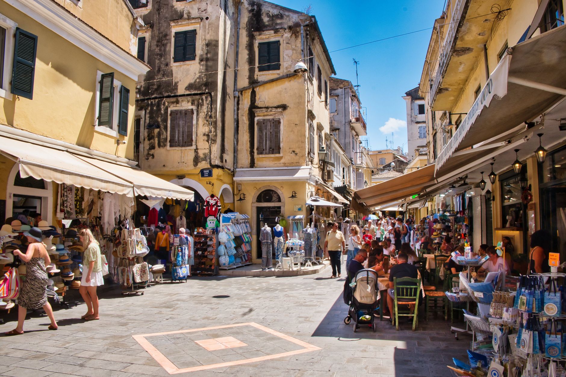 A bustling market town street full of shoppers and open cafes