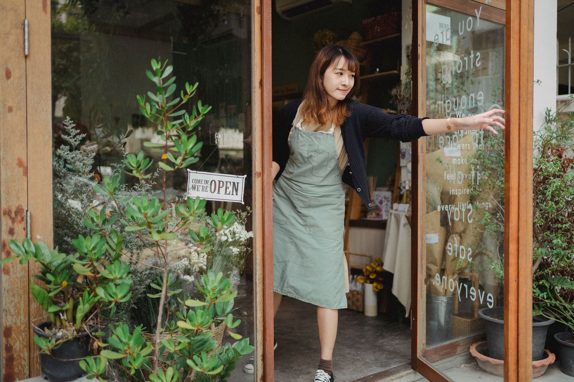 A shopkeeper updating a window display while keeping the shopfront consistent