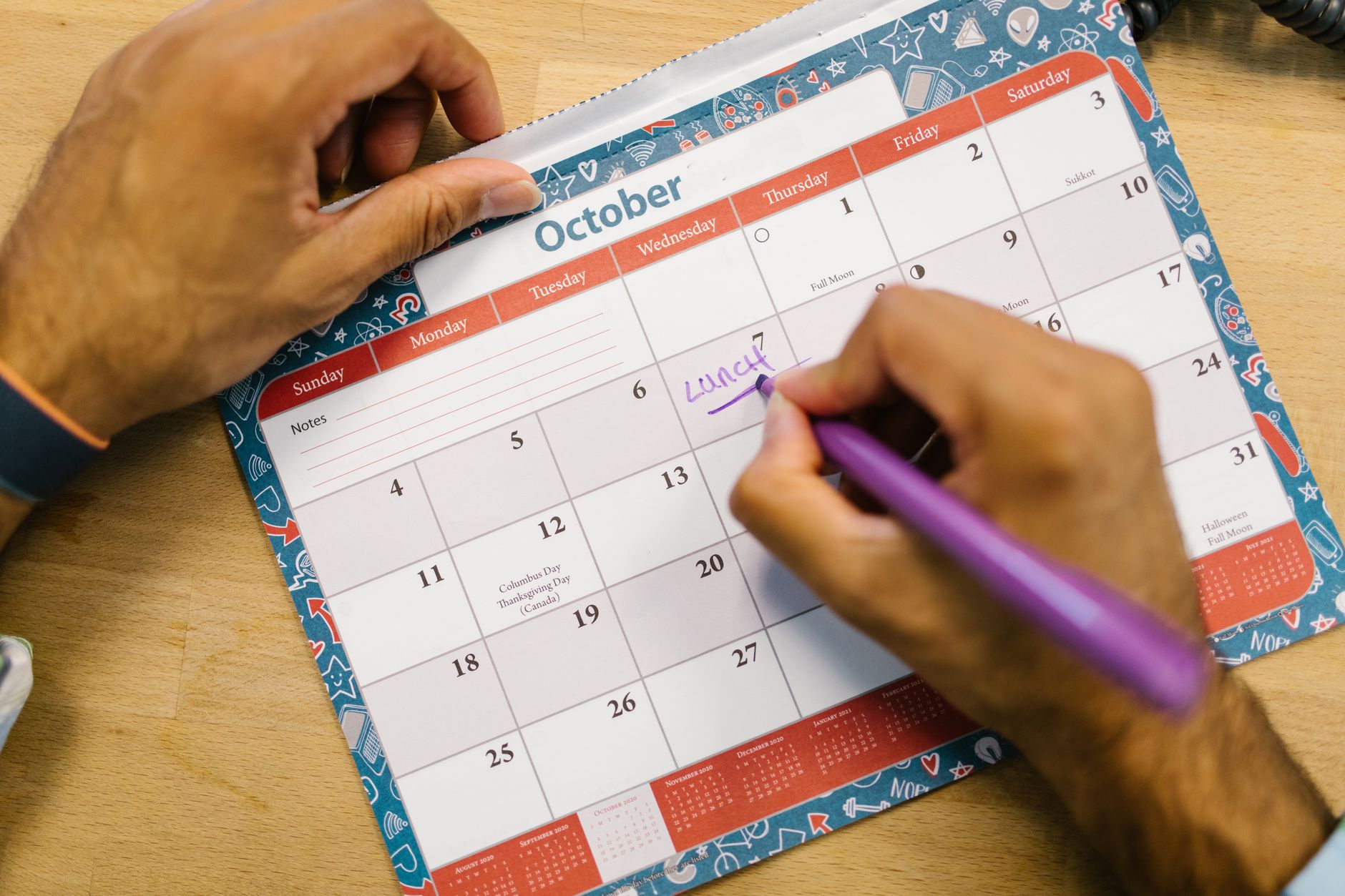 A business owner maps launch dates and a sequence of emails across a wall calendar at a desk, planning the offer window.