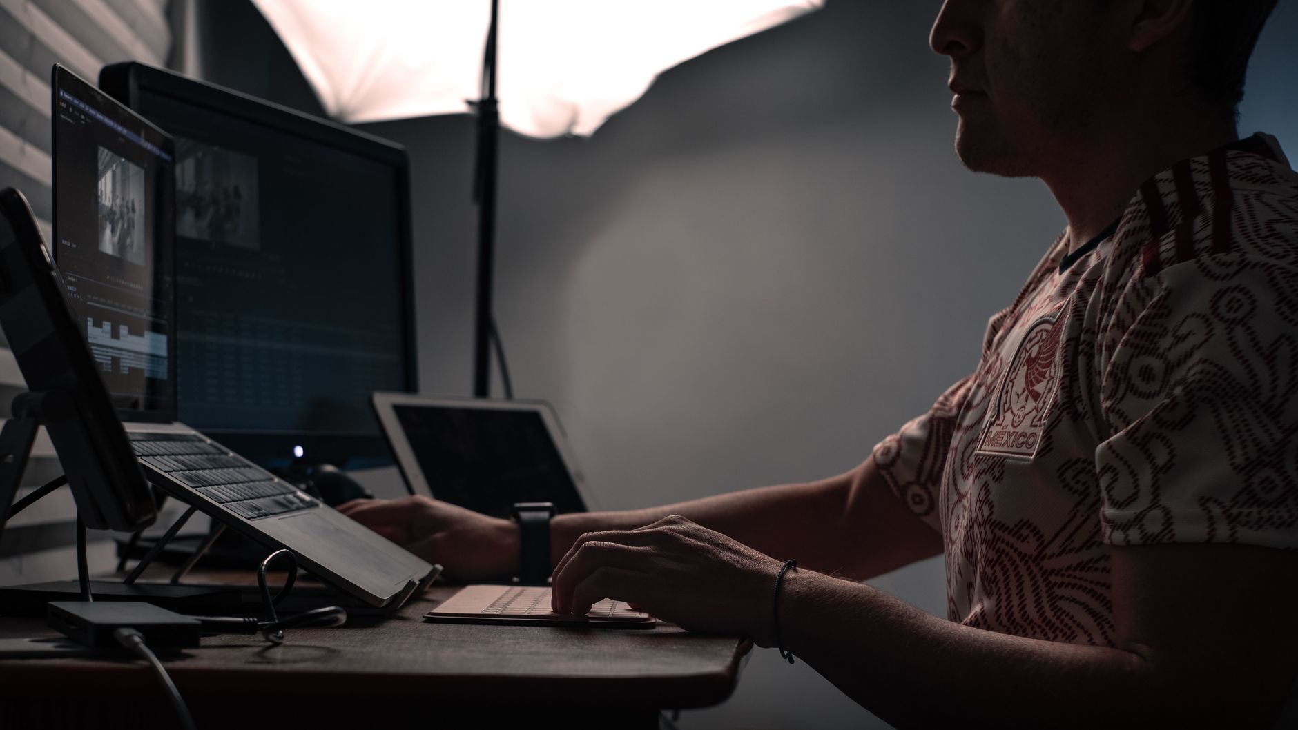 A small business owner works across a phone and laptop on launch day, posting the announcement and replying to early questions.