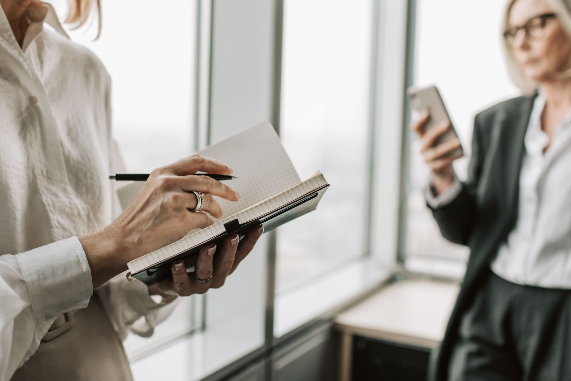 A cleaner replies quickly to a new enquiry on a smartphone with a job notebook open beside a mug of tea.