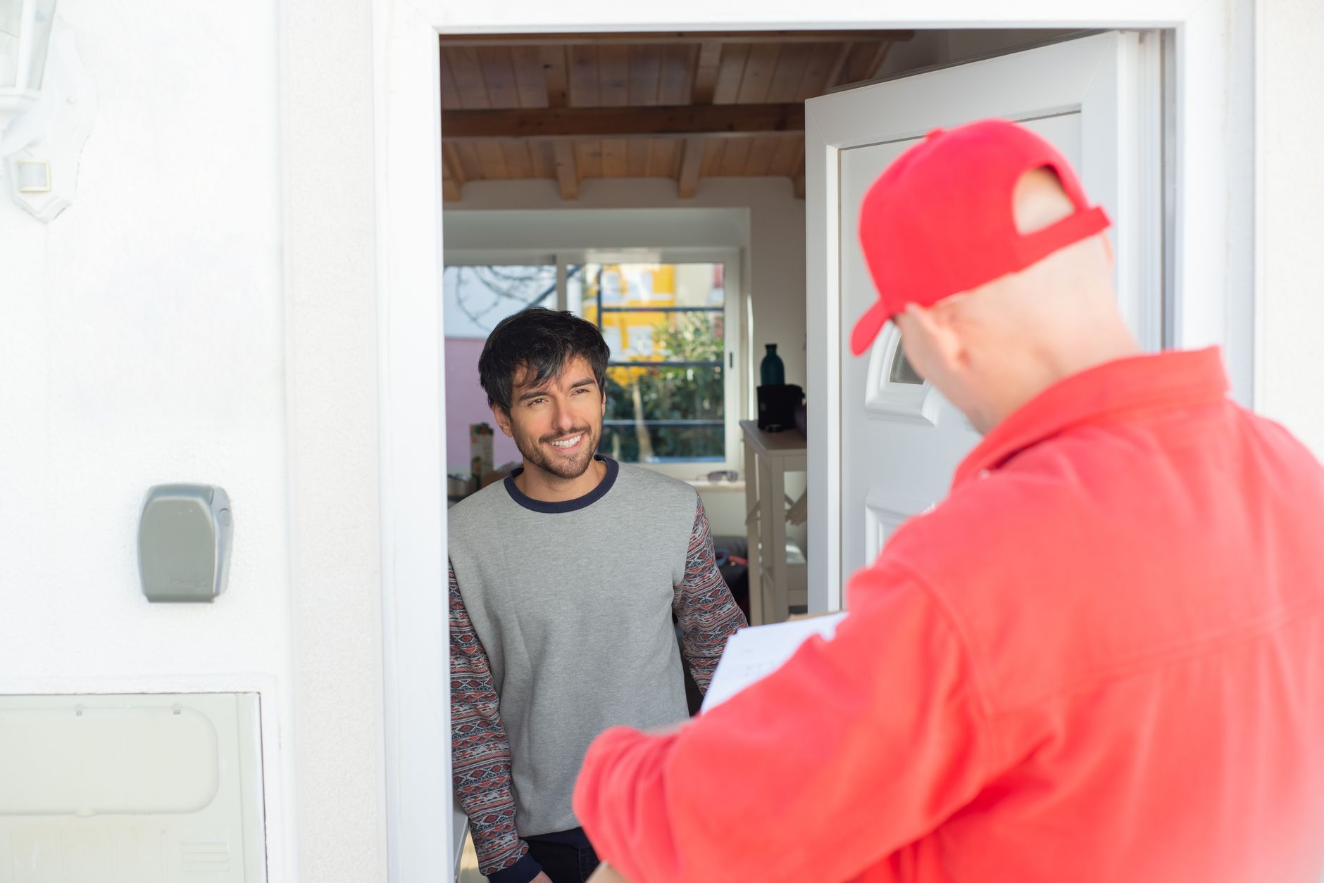 A cleaner is welcomed by a regular customer at the front door of a home for a scheduled weekly clean.