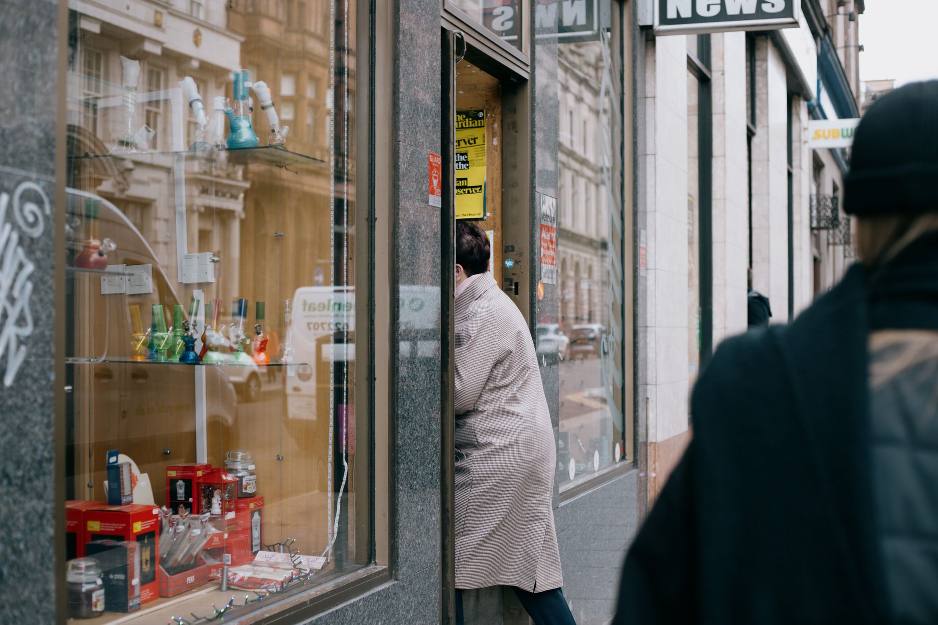 A first-time customer steps through the open doorway of a welcoming local shop with a clear sign above the entrance.