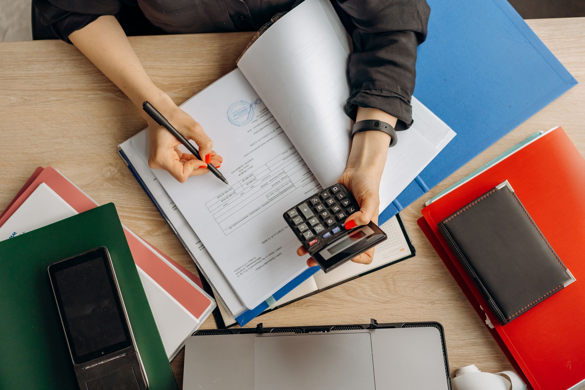 A home-cleaning business owner reviews monthly enquiry and conversion figures with a calculator and a handwritten notebook.