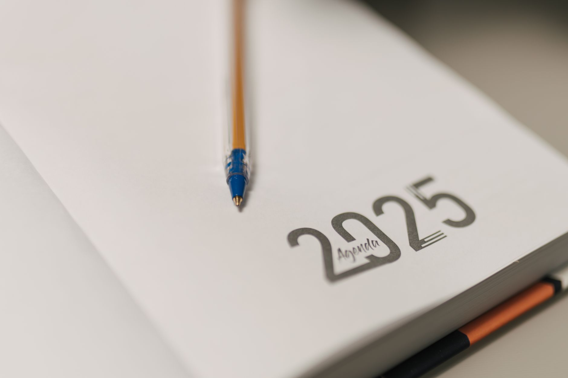 A business owner marks a date in a diary to review their rates, planning an annual price check at their desk.